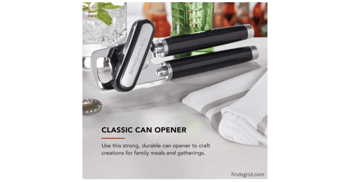KitchenAid Classic can opener lying on a kitchen counter next to a towel.