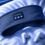 Sleep headband and wireless earbuds side by side on a pillow