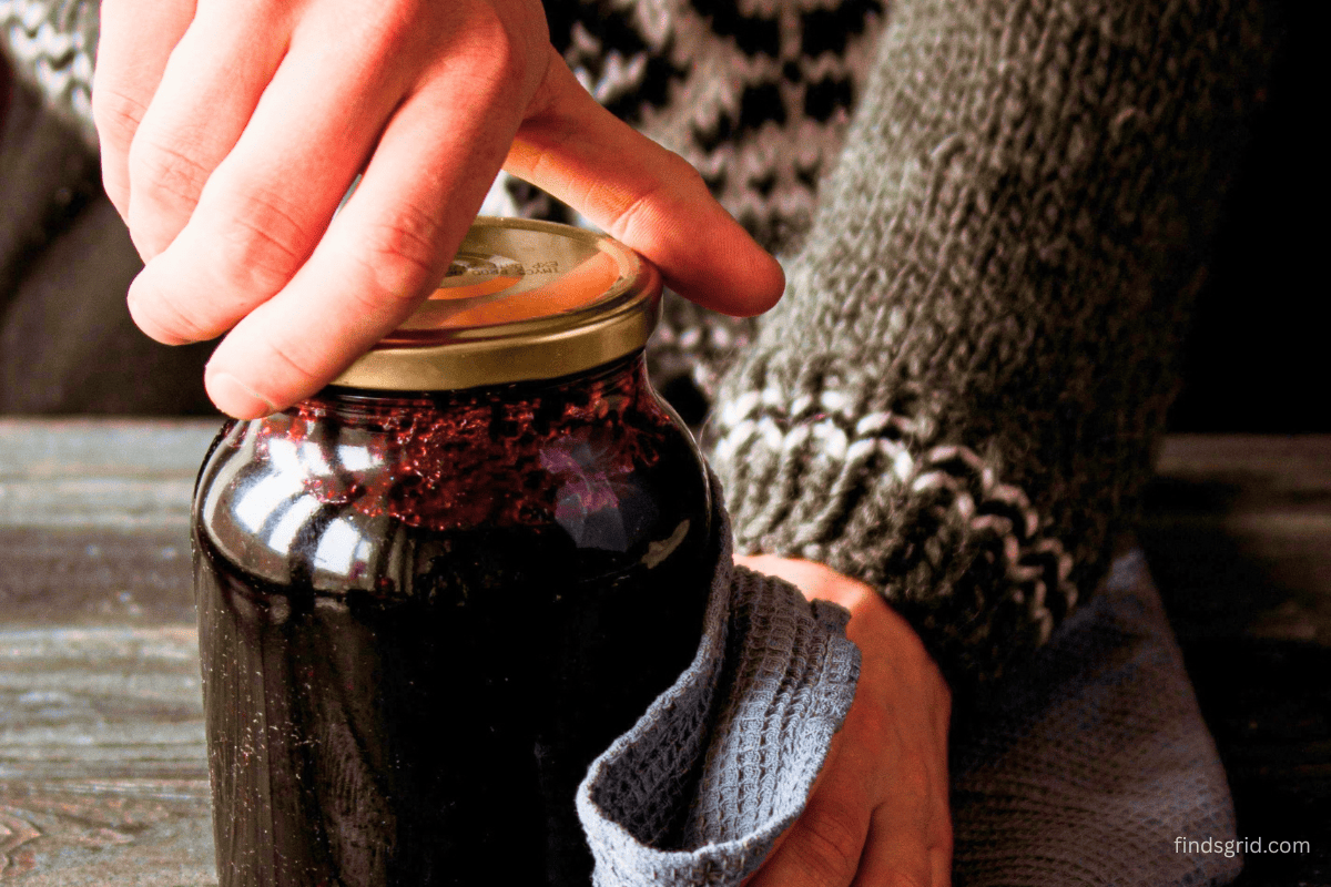 close-up of a hand struggling to twist a tight jar lid