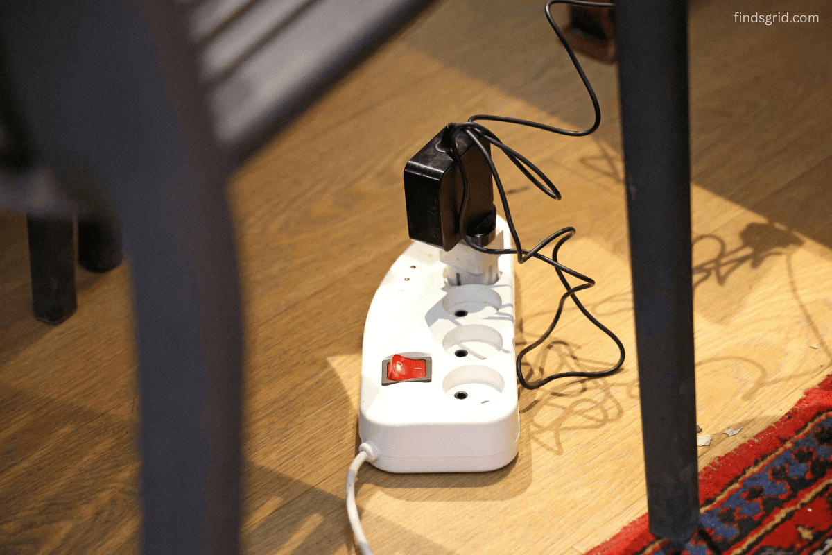 Tangled charging cables on bedroom floor near bed