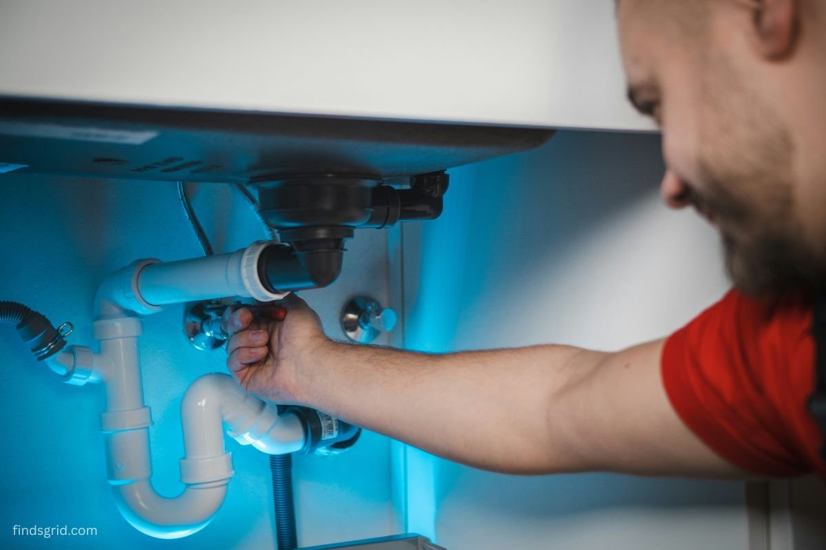 Plumber repairing a pipe under a kitchen sink