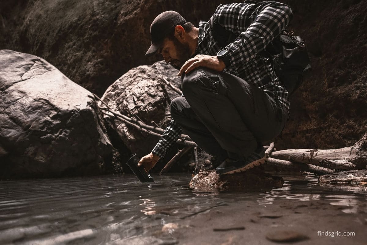 Hiker using a backcountry water filter beside a stream