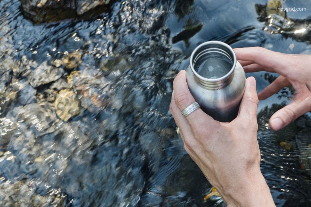 Hiker collecting creek water just below the surface before filtering
